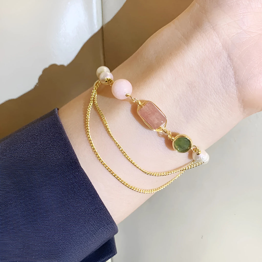 Close-up of a women's pink freshwater pearl bracelet with geometric links and strawberry crystal charms.
