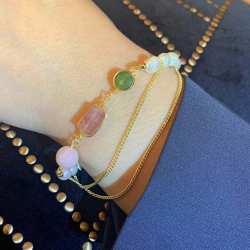 Close-up of a women's pink freshwater pearl bracelet with geometric links and strawberry crystal charms.