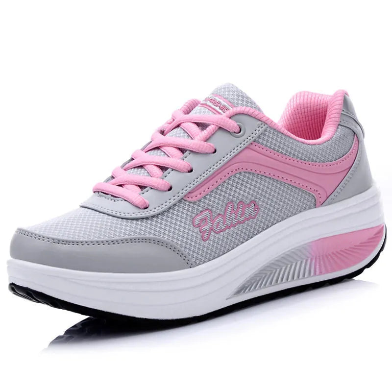 Women's grey pink heelless sports travel shoes with a mid heel on a neutral background.