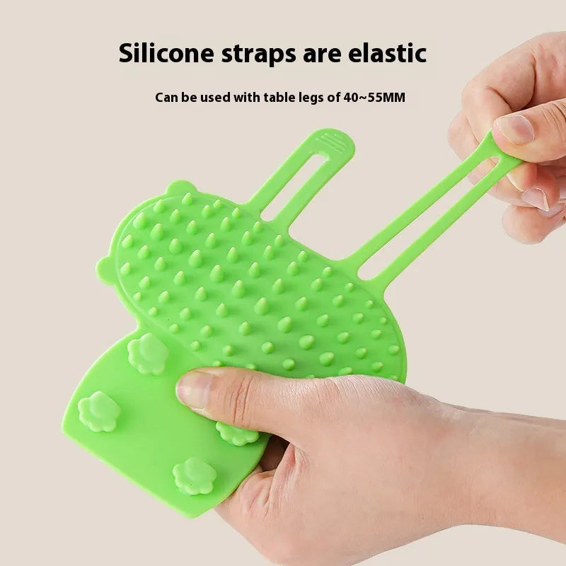 Silicone cat self-grooming brush with comb teeth and adjustable strap for table legs.