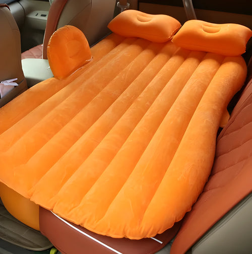 Black inflatable car bed with flocked surface and two pillows, shown inside a vehicle.