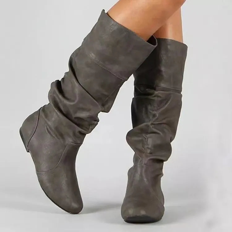 Women's black slip-on flat boots with round toe and high cylinder design on a neutral background.
