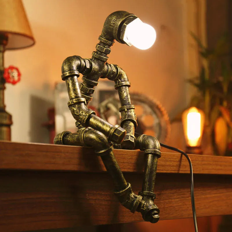 Green bronze vintage industrial robot desk lamp with iron pipe design on a wooden table.