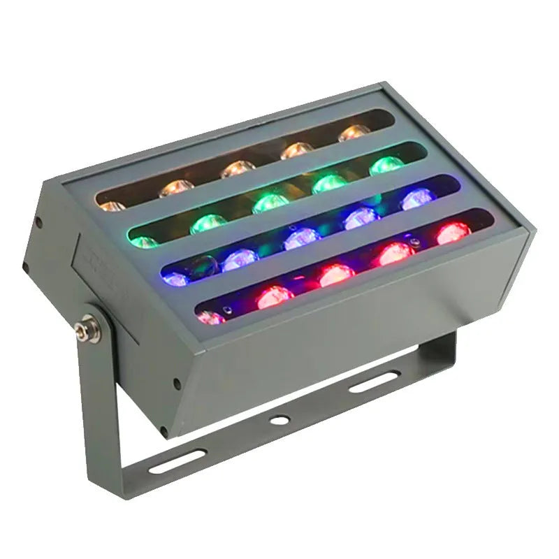 Silver aluminium outdoor LED spotlight projecting multi-coloured light onto trees.