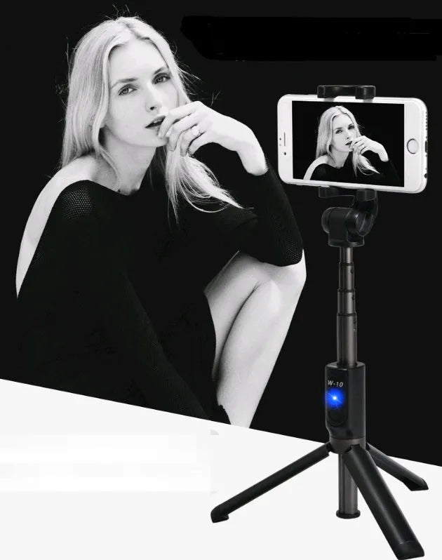 Black Bluetooth selfie stick tripod with remote control extended next to mobile phone