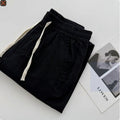 Men's beige loose-fit straight-leg casual pants with a drawstring waistband on a hanger.