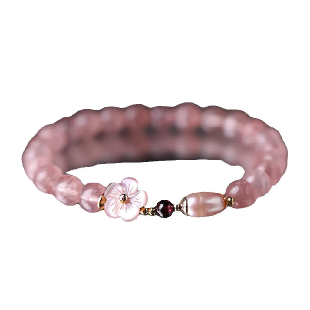 Women's strawberry quartz crystal bracelet with a floral peach blossom design on a wrist.