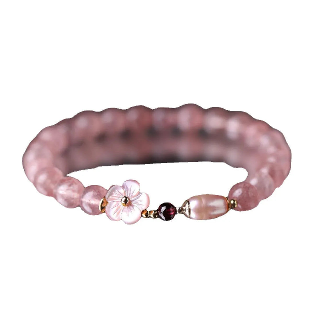Women's strawberry quartz crystal bracelet with a floral peach blossom design on a wrist.