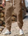 Men's beige straight leg linen trousers with elastic waistband laid flat