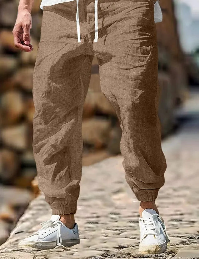 Men's beige straight leg linen trousers with elastic waistband laid flat