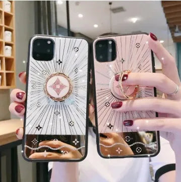 Gold-tone phone stand with diamond crystals holding iPhone and rings