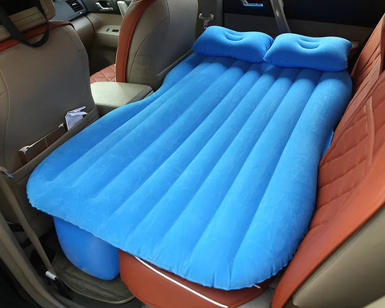 Black inflatable car bed with flocked surface and two pillows, shown inside a vehicle.