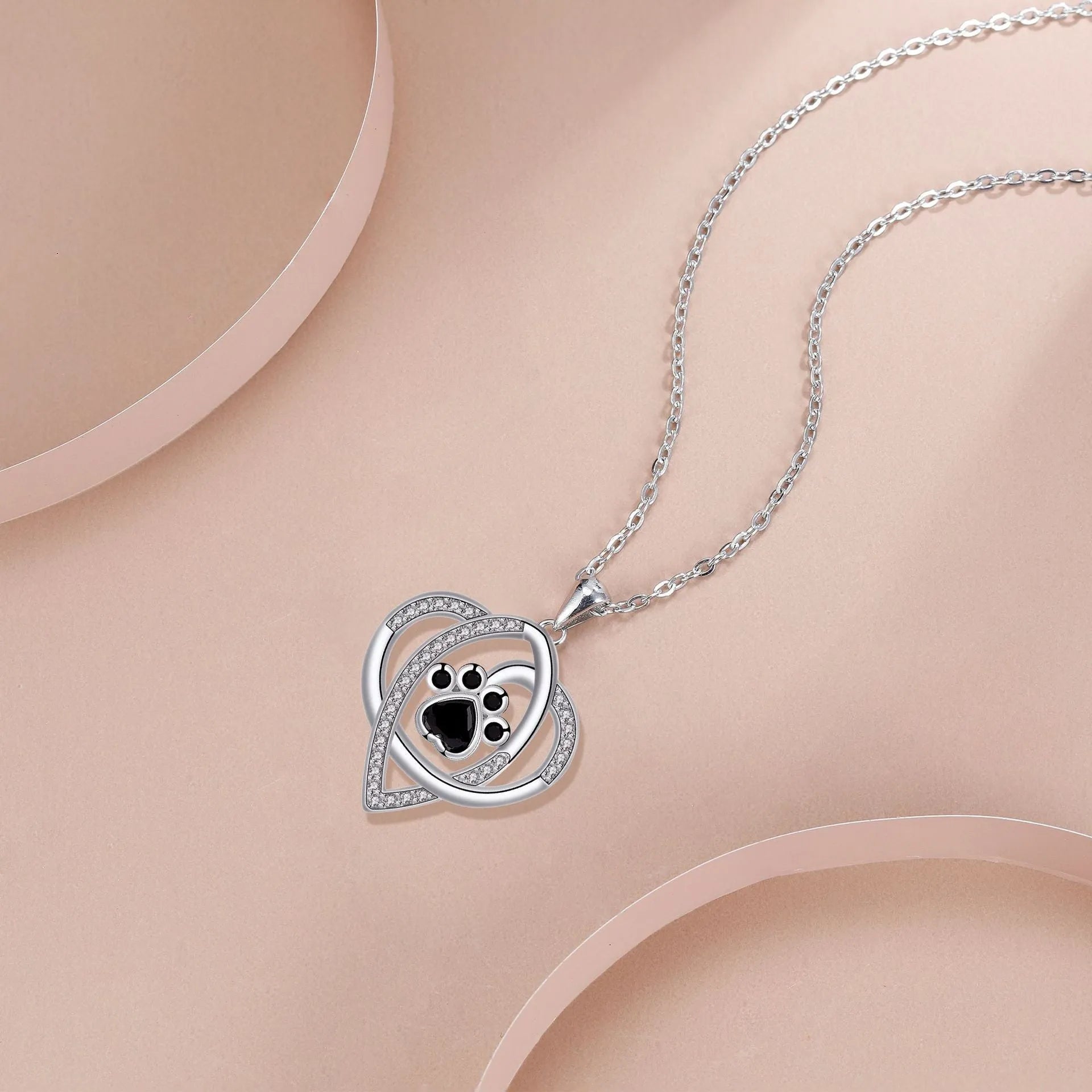 Close-up of a copper necklace pendant showing detailed dog and cat paw prints on a cross chain.