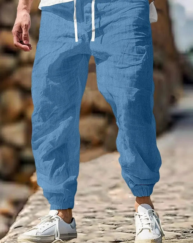 Men's beige straight leg linen trousers with elastic waistband laid flat