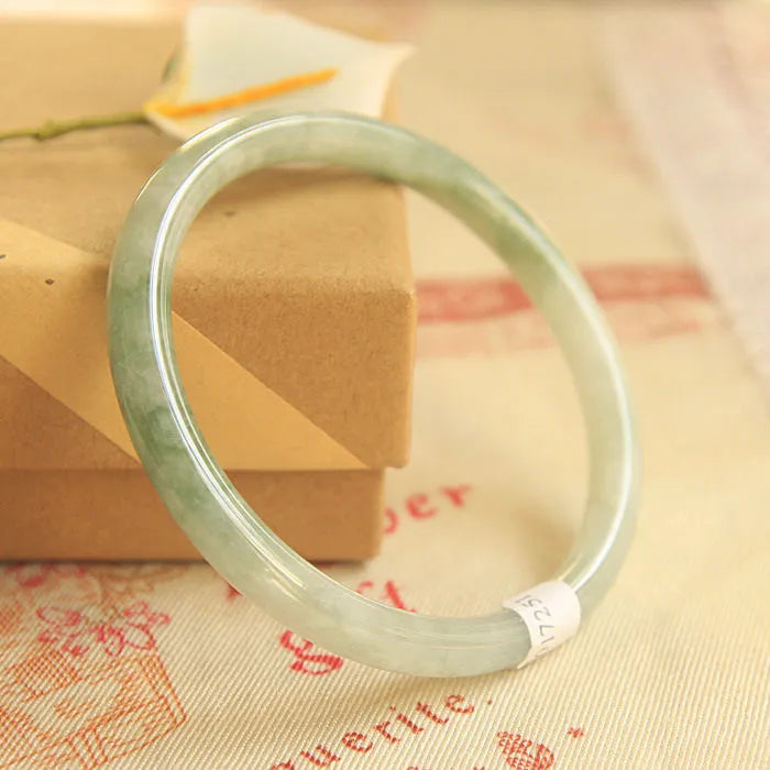 Green jade waxy geometric bead bracelet with adjustable cord on a plain background.