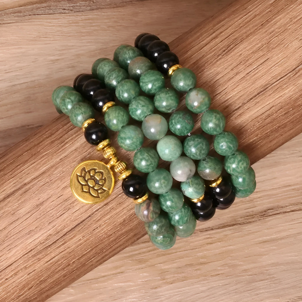Green and black elastic beaded bracelet with metallic alloy charm details on a wrist.