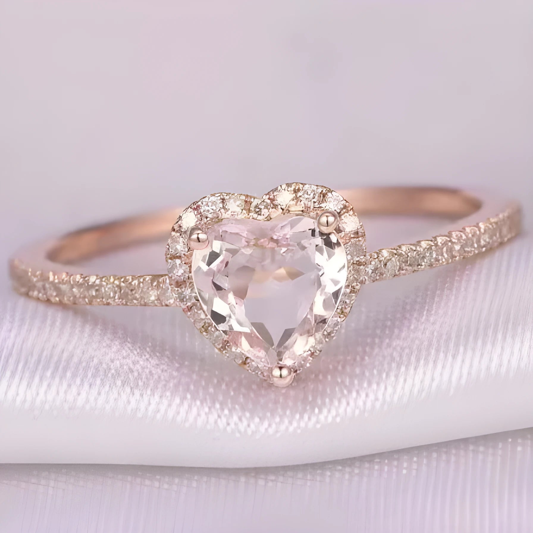 Close-up of a women's heart-shaped ring with a clear crystal centre in rose gold or silvery finish.