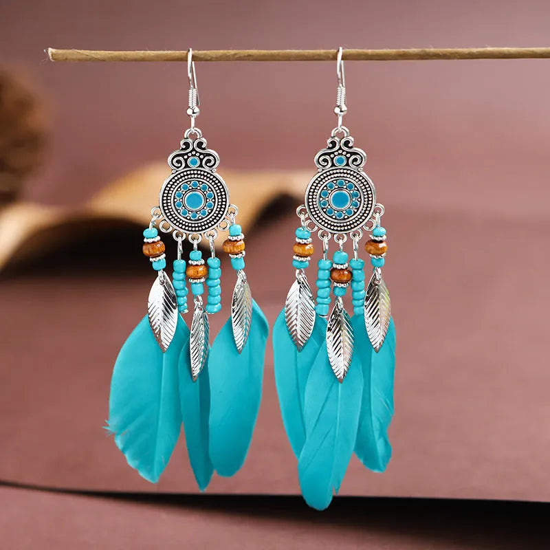A pair of round drop leaf-shaped feather earrings in a chosen colour, showing Bohemian pattern details.