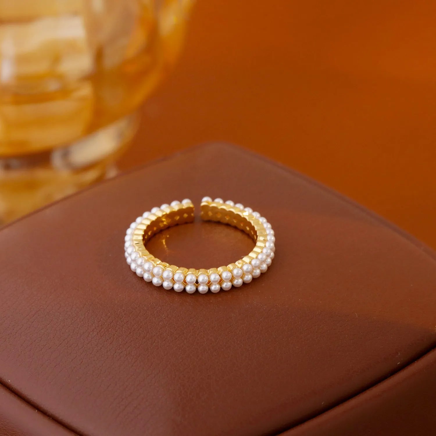 Gold-coloured women's open ring with geometric design and a round pearl-like bead.