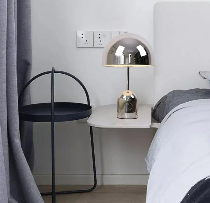 Mushroom shaped metal table lamp in rose gold finish on a wooden surface.