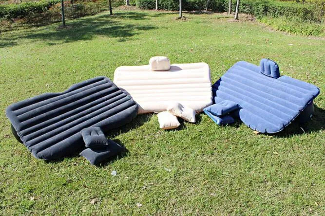 Black inflatable car bed with flocked surface and two pillows, shown inside a vehicle.