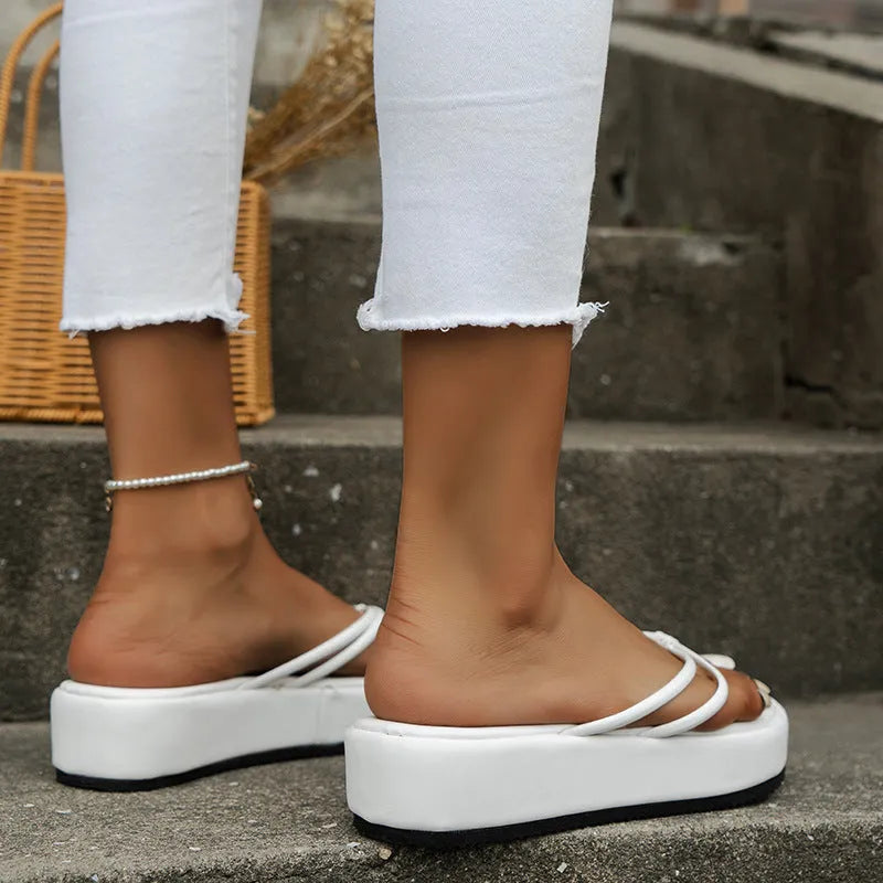 White thick bottom flip-flops with herringbone pattern and round toe on a rubber sole.