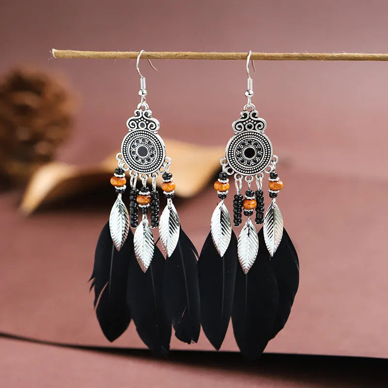 A pair of round drop leaf-shaped feather earrings in a chosen colour, showing Bohemian pattern details.