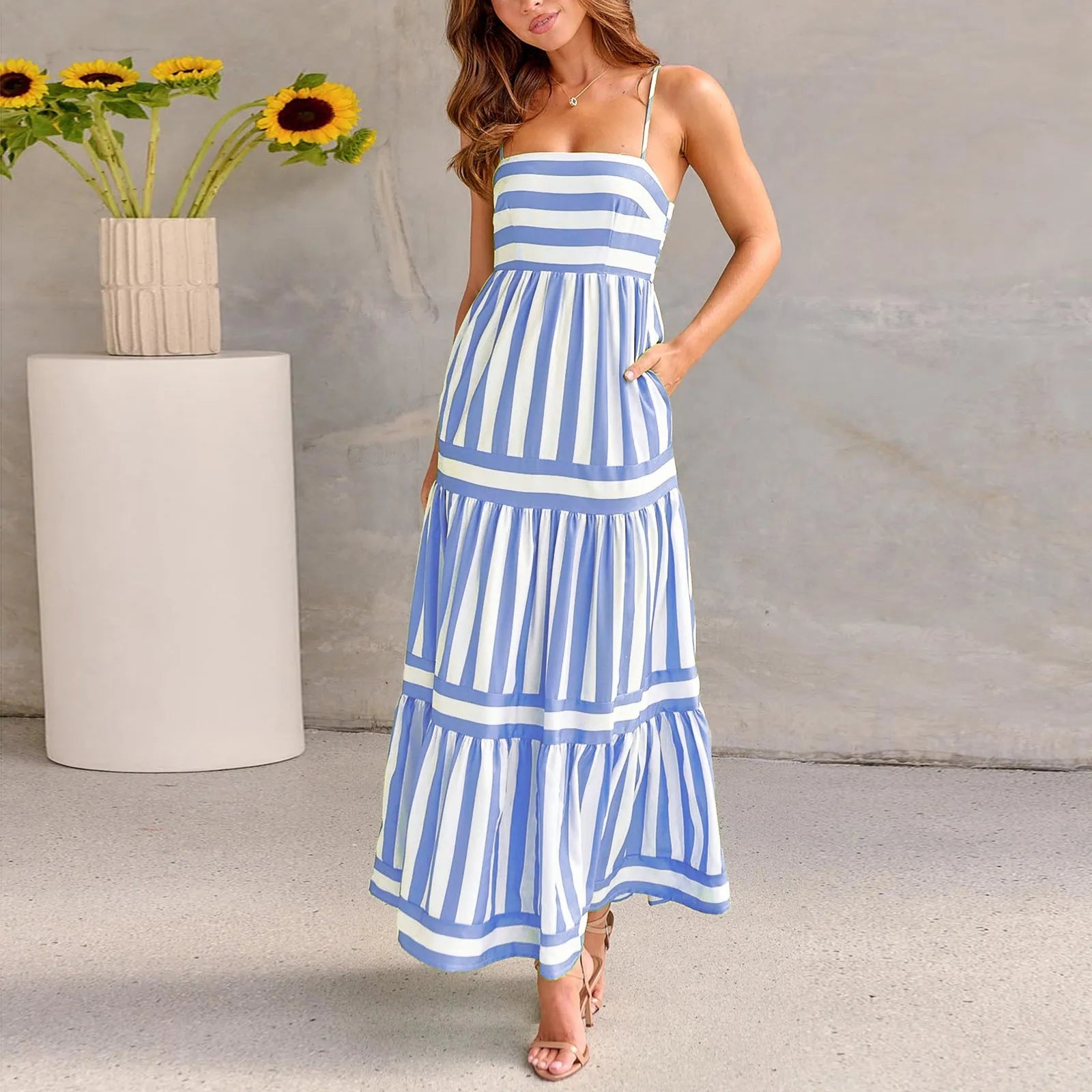A woman wearing a striped backless suspender summer dress with a square neckline and side pockets.