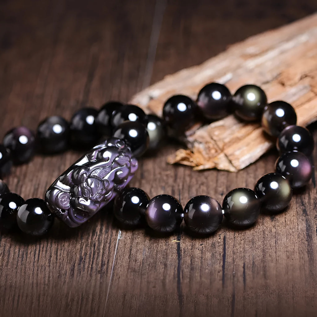 A polished crystal Pi Xiu bracelet with geometric beads on a white background.