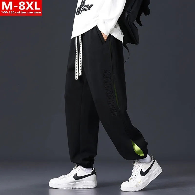 Man wearing loose grey-green trousers with stitching print detail and ankle banding.