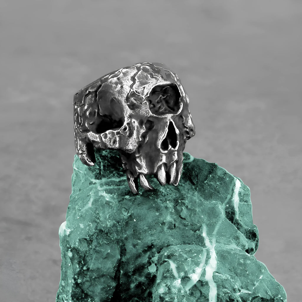 A close-up view of a silver-toned alloy ring featuring a detailed one-eyed skull design in a retro punk style.