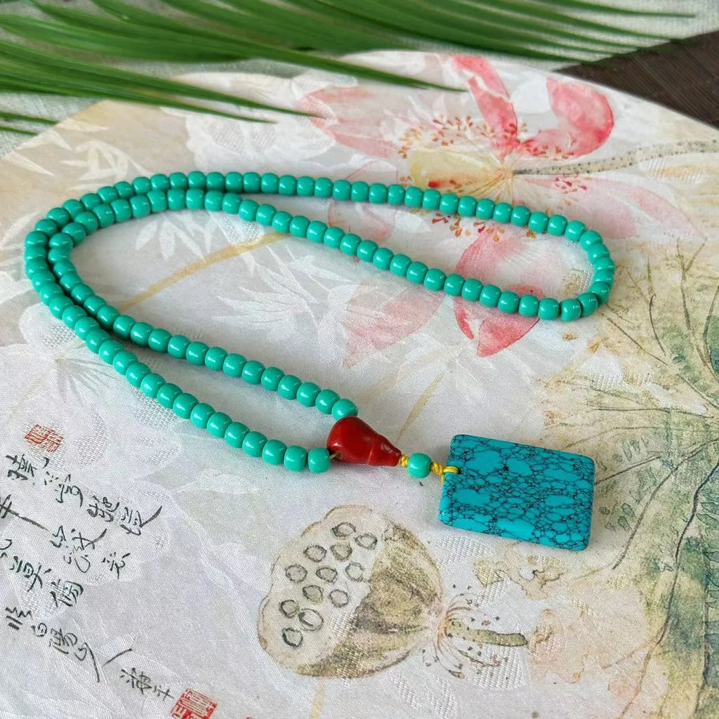 Hand-woven turquoise mesh flower lucky pendant on a ball bead necklace chain, adjustable length.