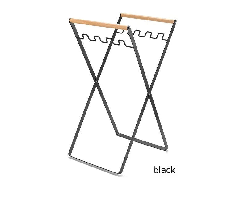 Black iron folding storage rack with a wooden handle for hanging outdoor waste bags.