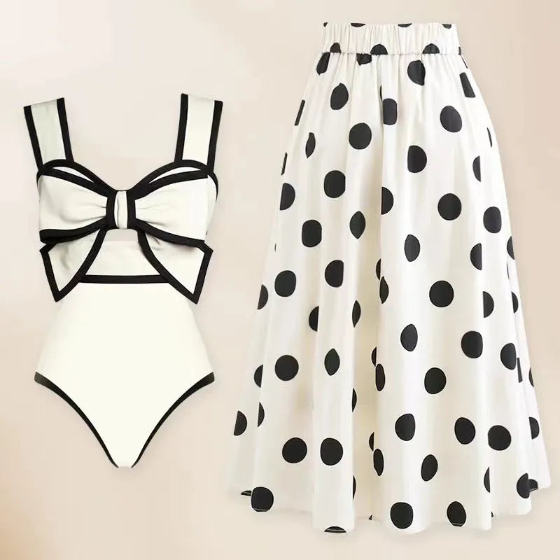 Black one-piece women's swimsuit with a flared round skirt and a decorative bow on the front.