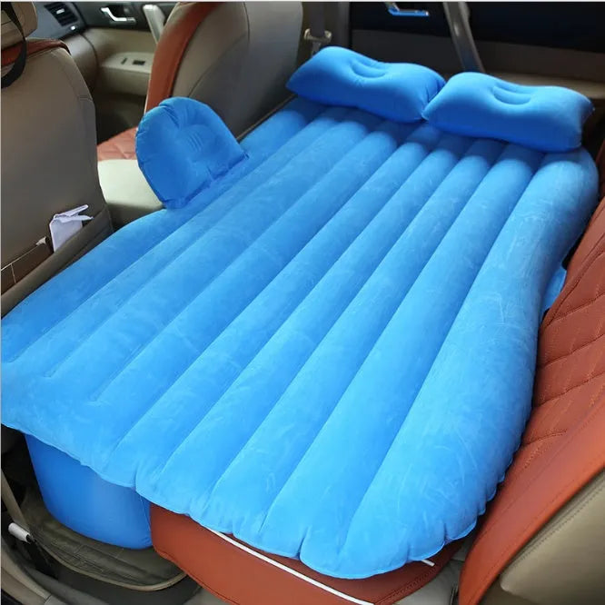 Black inflatable car bed with flocked surface and two pillows, shown inside a vehicle.