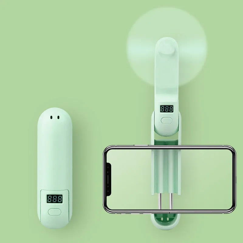 Green folding mini fan with leaf-shaped plastic blades, shown open and ready for use