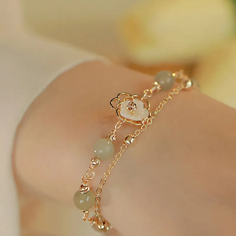 Yellow gold electroplated copper bracelet with a geometric bells of Ireland butterfly and Hetian jade design for women.