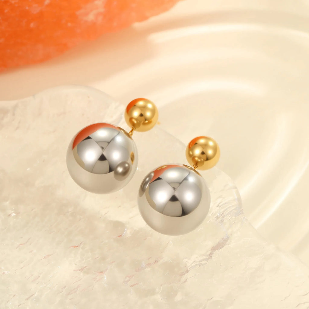 A pair of stainless steel stud earrings with 18K gold electroplated colour-block finish and round bead geometry design.