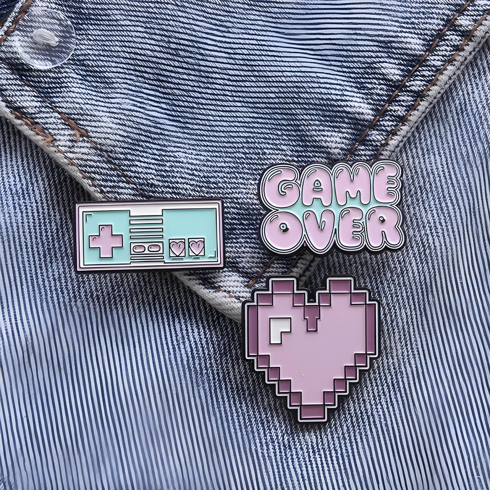 Stereo game console metal badge in protective OPP packaging, shown in one of three colour variants.