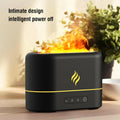 Black USB humidifier displaying a seven-colour flame effect on a desk next to a plant.