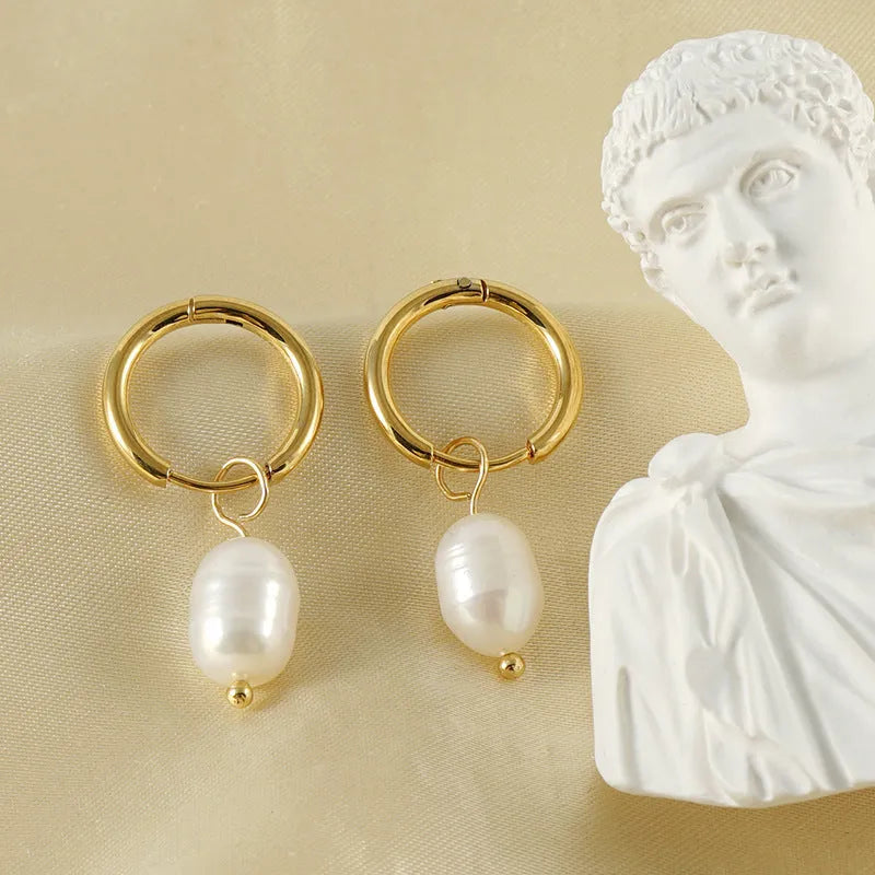 Geometric gold-coloured earrings with cultured pearl details on a white background.