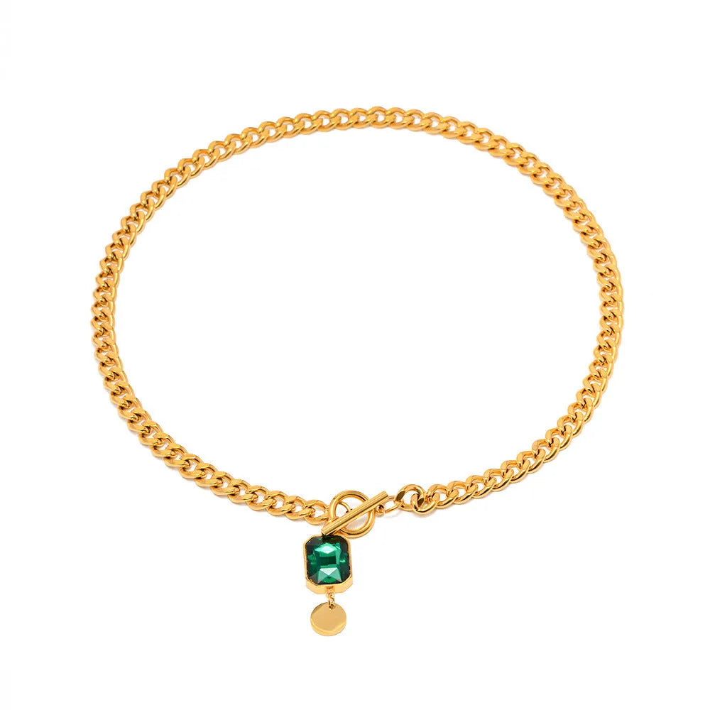 Gold electroplated titanium steel pendant necklace with geometric design and emerald zircon accents on Cuban link chain