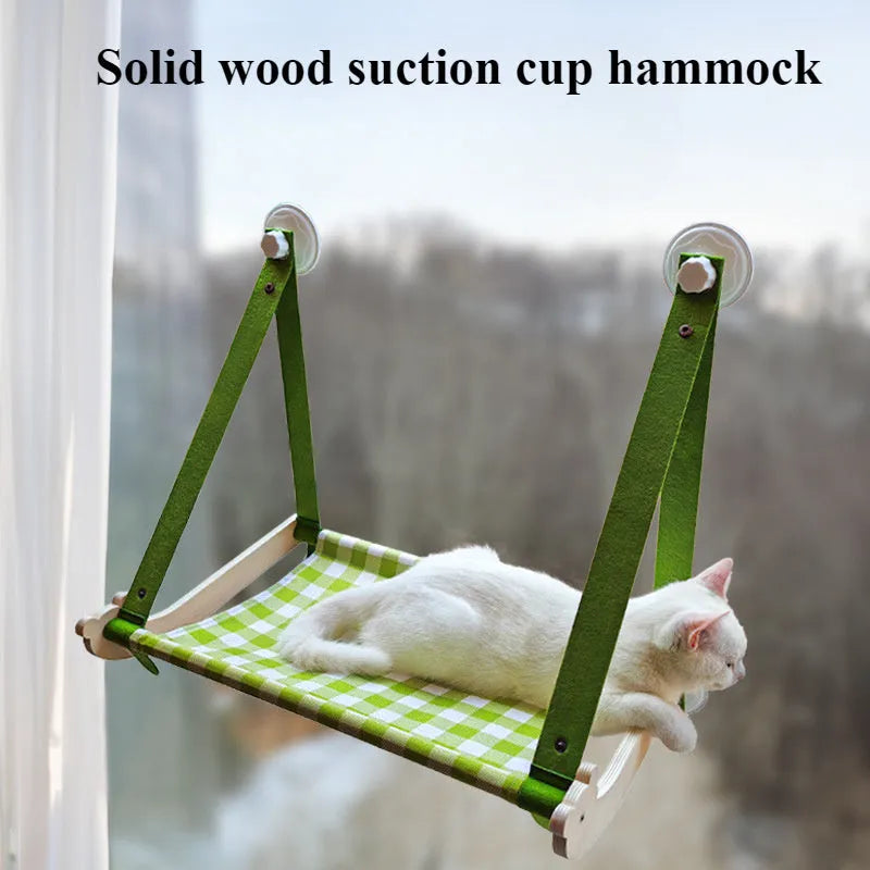 Wooden frame cat hammock with linen cushion mounted on a window, shown in green colour.
