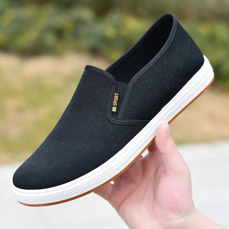 Men's black low-top slip-on canvas shoes with a round toe and composite sole on a white background.