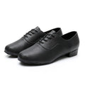 Men's black dancing shoes with a synthetic leather upper and calf leather sole, shown on a studio floor.