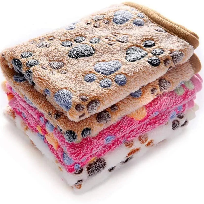 Coral fleece dog blanket with paw print pattern in beige, shown in a large size on a dog bed.