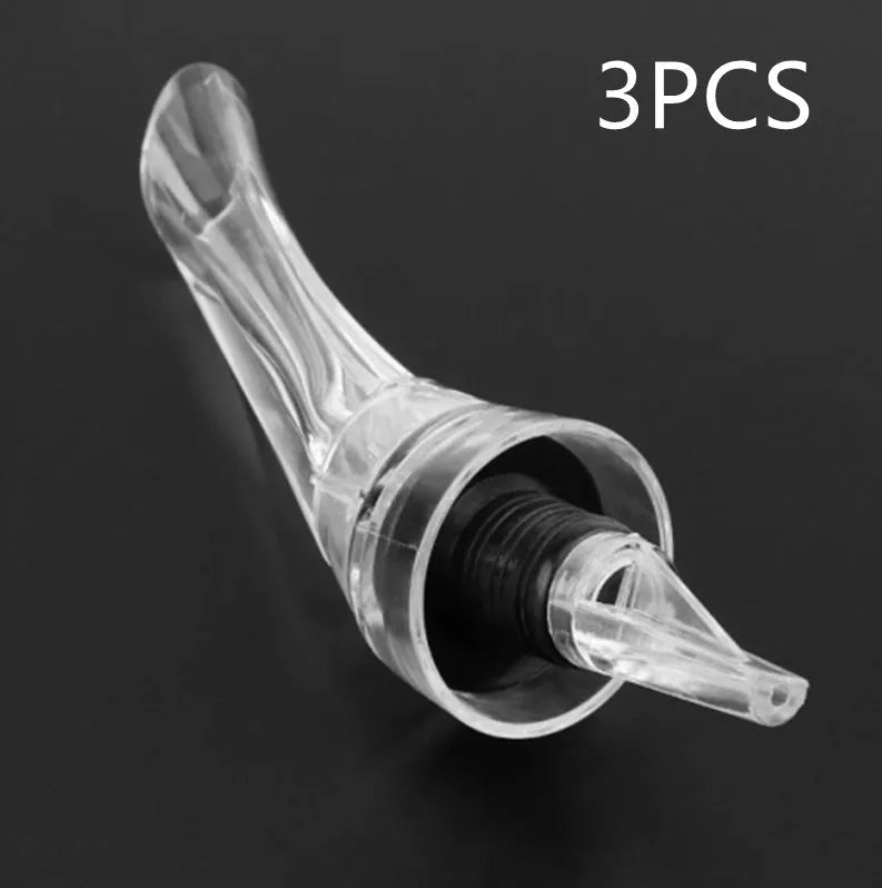 Compact clear acrylic wine aerator with a stainless steel filter insert on a wooden table.