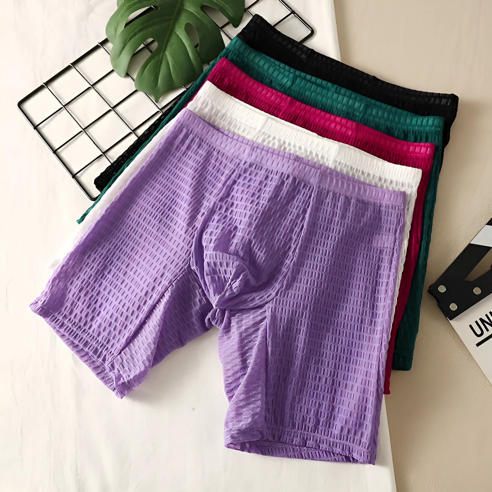 Men's lace boxer underwear in light purple on a grey background, showing the lengthened hip lift design.