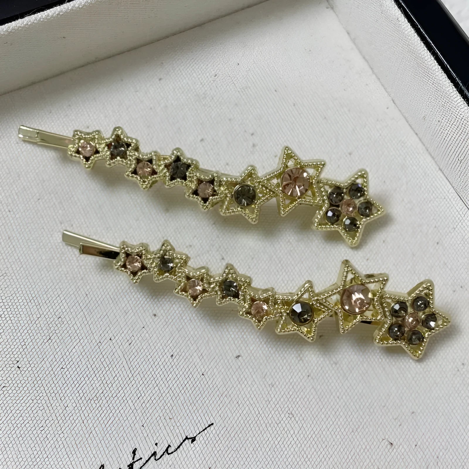 Gold electroplated alloy barrette with five-pointed star rhinestone design and broken clip construction
