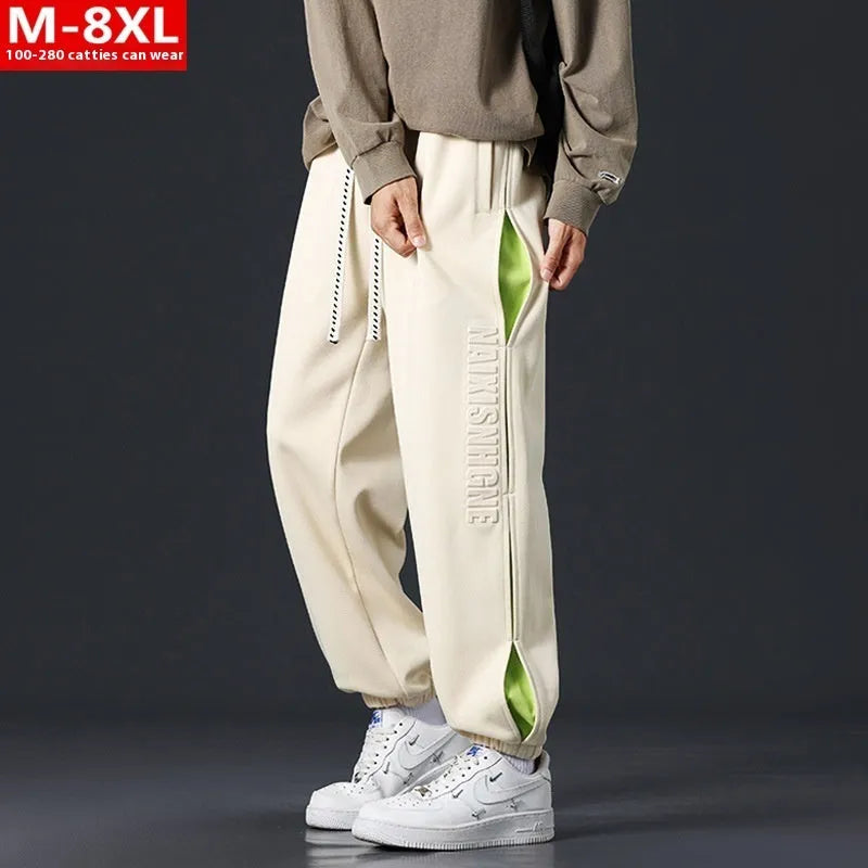 Man wearing loose grey-green trousers with stitching print detail and ankle banding.